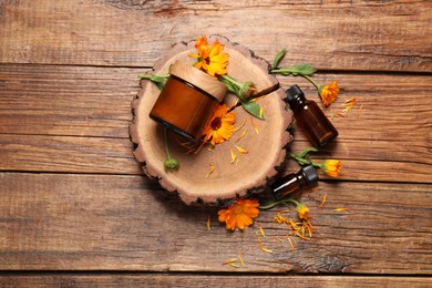 Different cosmetic products and beautiful calendula flowers on wooden table, flat lay