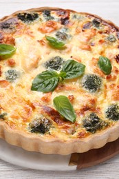 Photo of Delicious homemade quiche with salmon, broccoli and basil leaves on table