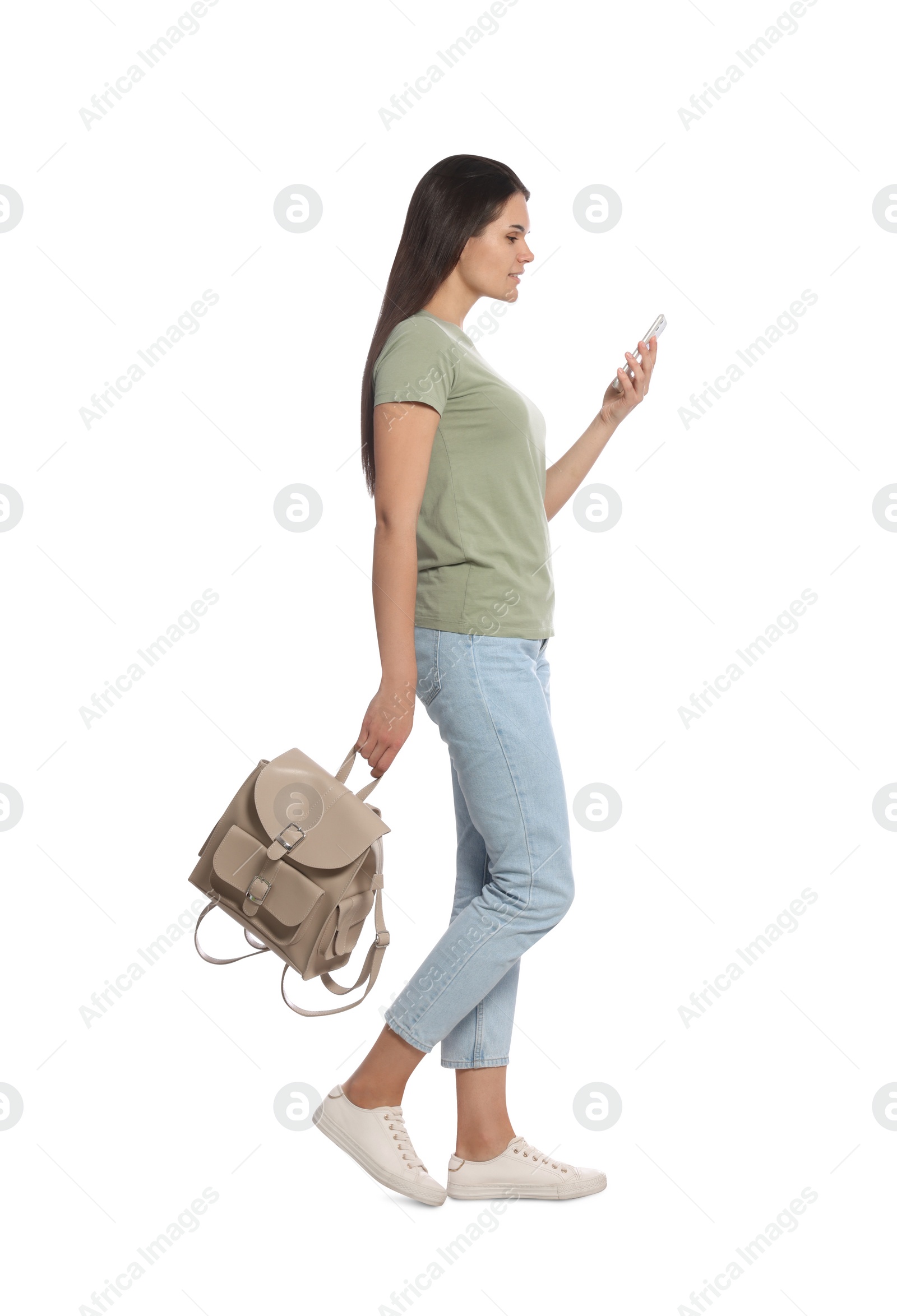 Photo of Young woman with smartphone and leather backpack walking on white background