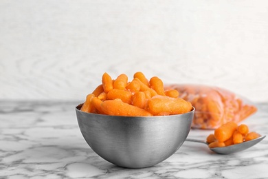 Bowl with frozen carrots on table. Vegetable preservation