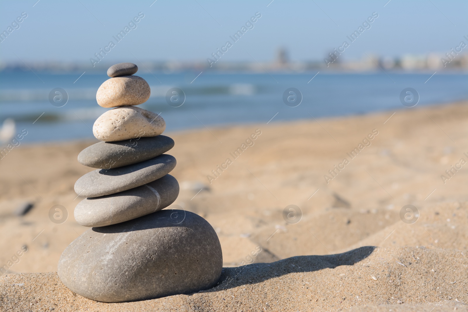 Photo of Stack of stones on sandy beach, space for text