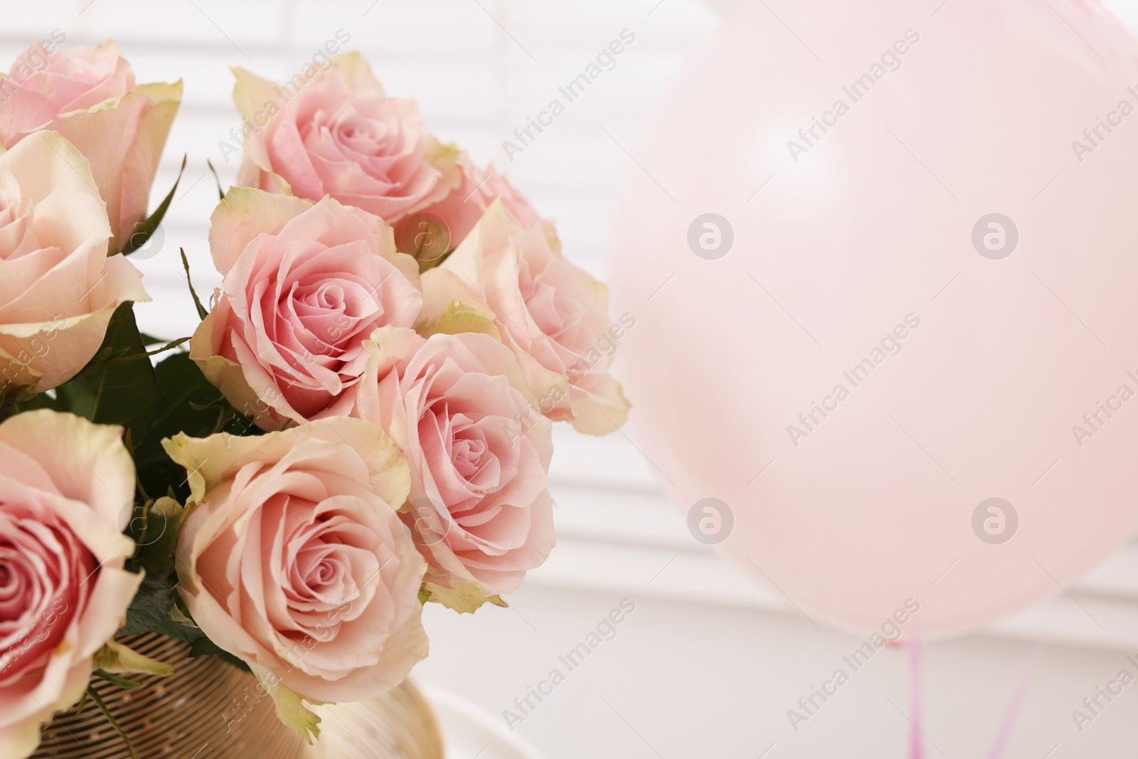 Photo of Beautiful bouquet of rose flowers in vase and air balloon indoors. Happy birthday