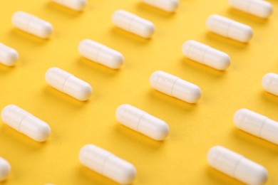 Photo of Many vitamin capsules on orange background, closeup