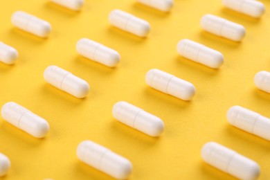 Many vitamin capsules on orange background, closeup