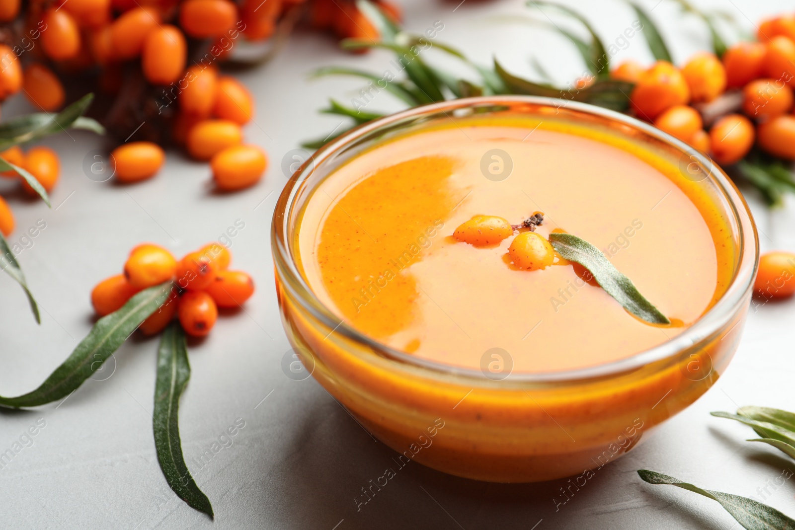 Photo of Delicious sea buckthorn jam and fresh berries on light grey table