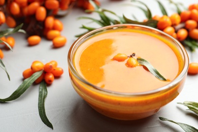 Delicious sea buckthorn jam and fresh berries on light grey table