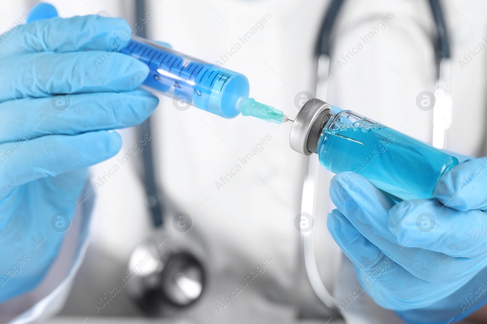 Photo of Doctor filling syringe with medication from glass vial, closeup