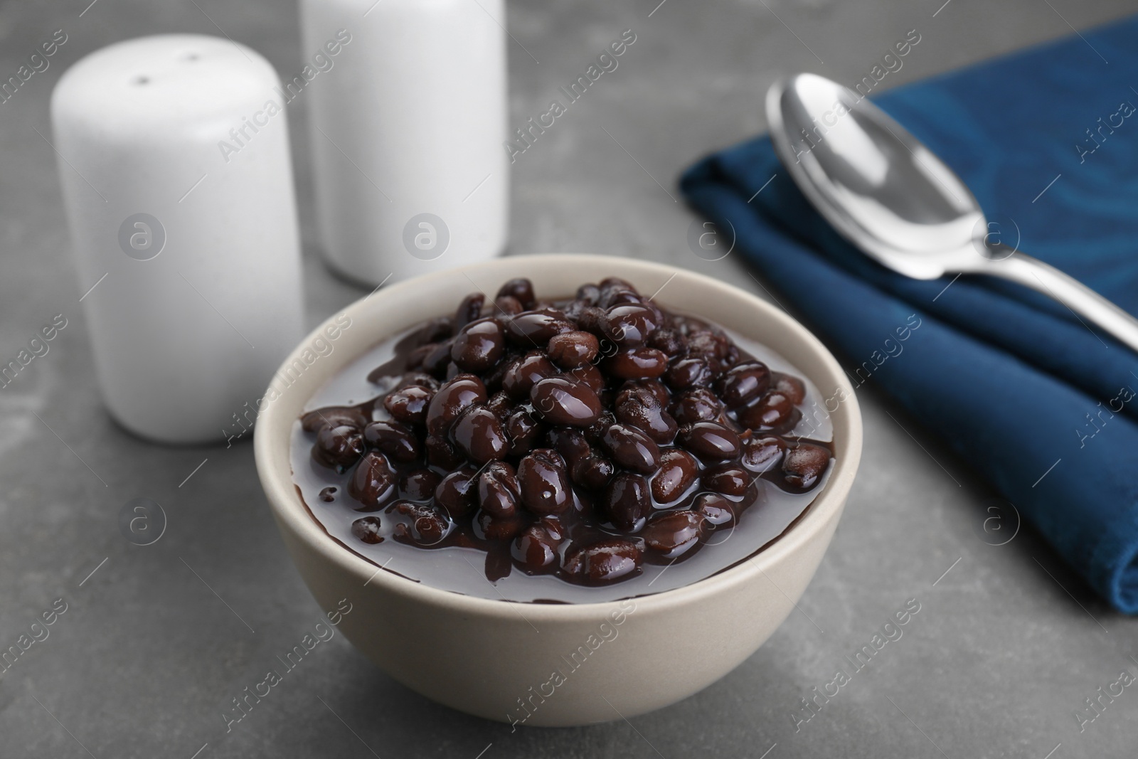 Photo of Bowl of canned kidney beans on grey table, closeup