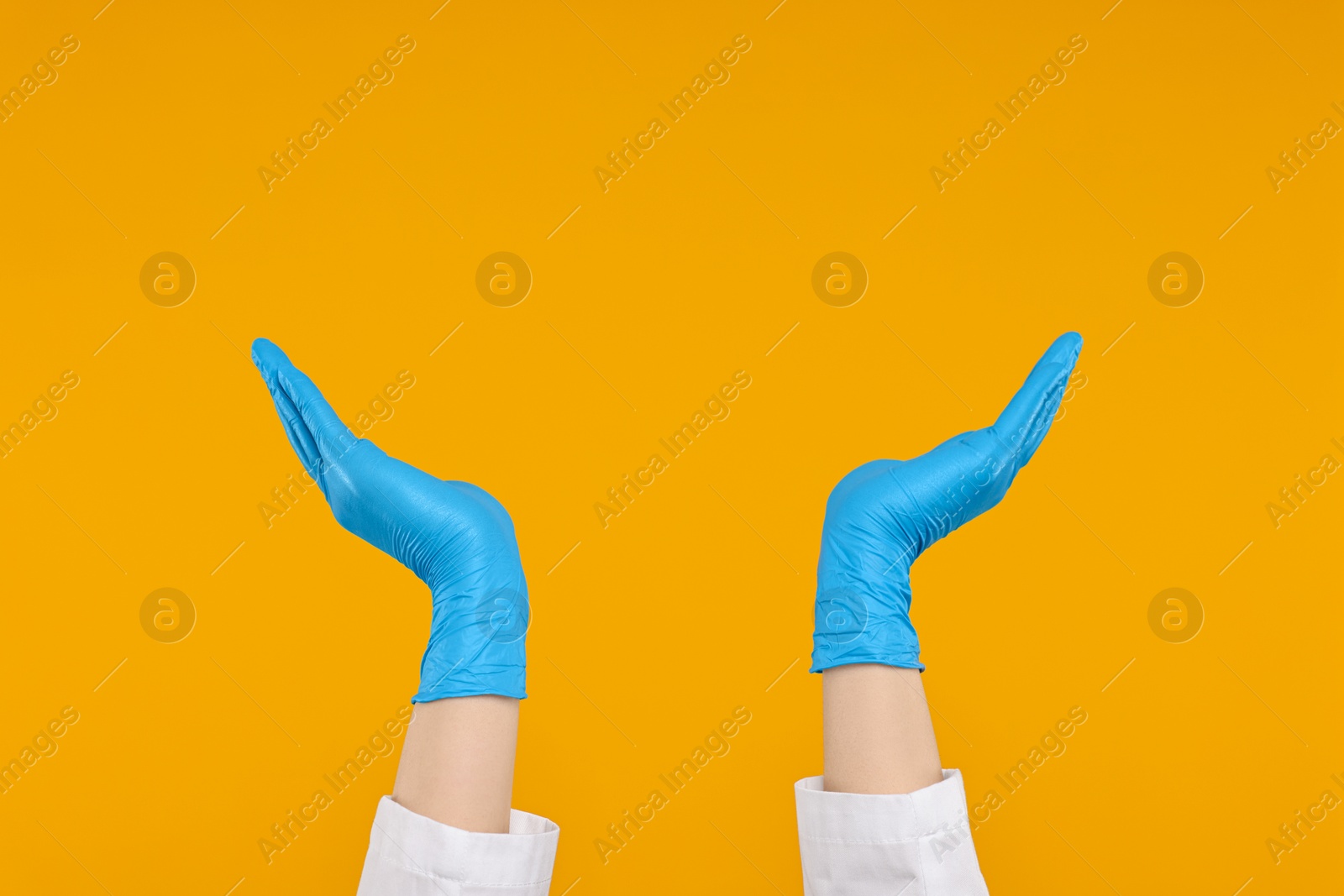 Photo of Doctor holding something on orange background, closeup. Space for text
