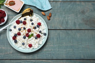 Photo of Delicious cottage cheese with fresh berries and honey served on light blue wooden table, flat lay. Space for text