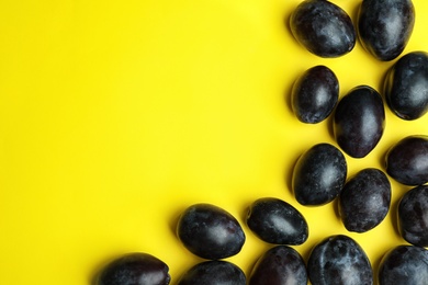 Delicious ripe plums on yellow background, flat lay. Space for text