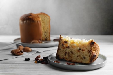 Slice of delicious Panettone cake with raisins on white wooden table, space for text. Traditional Italian pastry