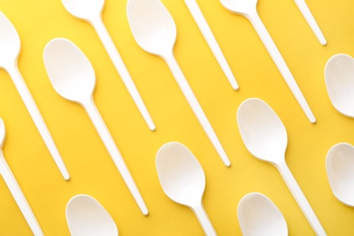 Photo of Plastic spoons on color background, top view. Picnic table setting