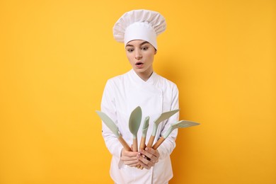 Photo of Professional chef with kitchen utensils on yellow background