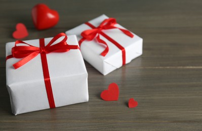 Photo of Beautiful gift boxes with red hearts on wooden table