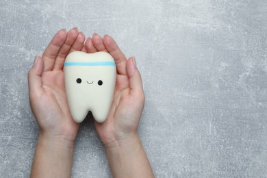 Photo of Woman holding tooth model at grey table, top view. Space for text