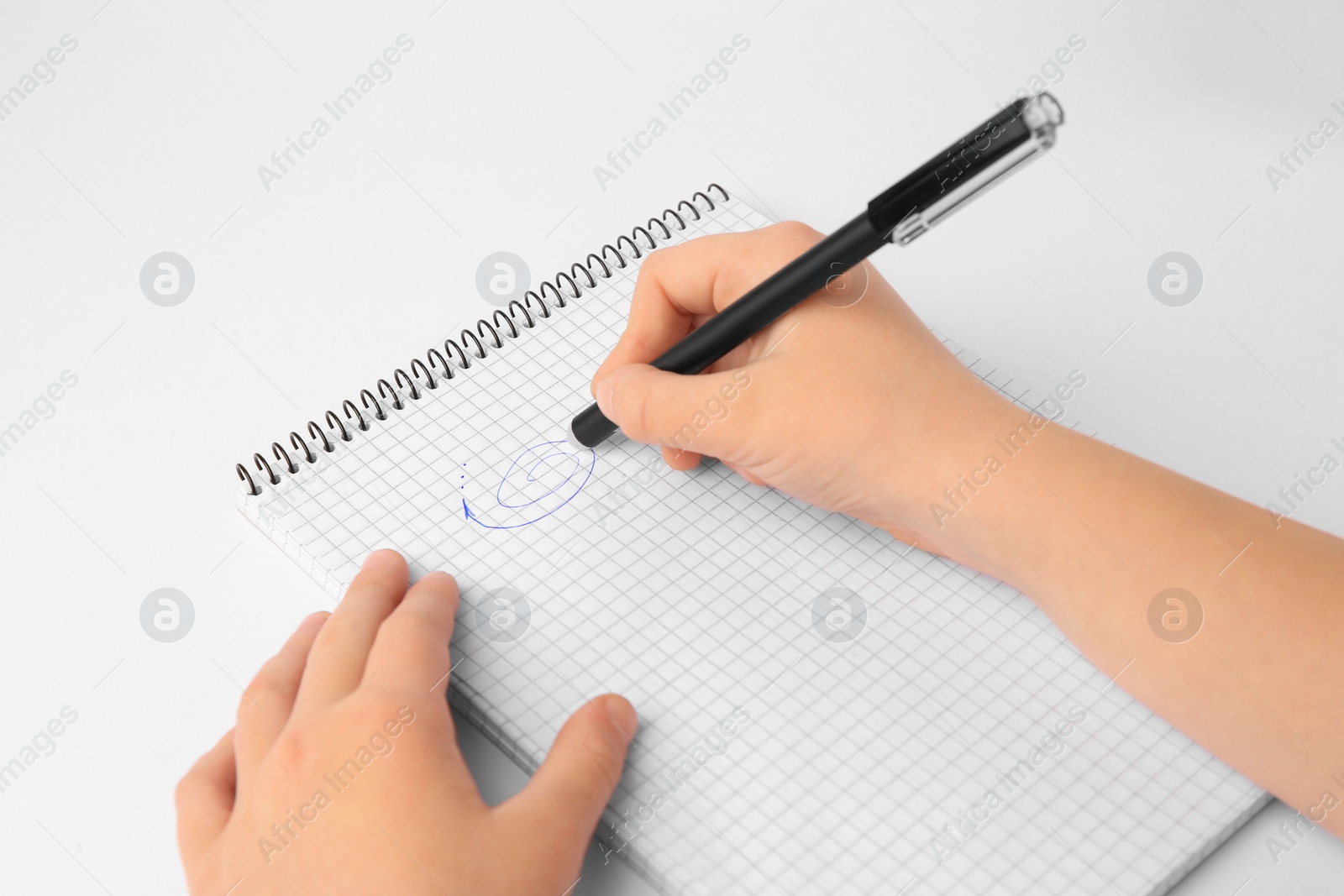 Photo of Child erasing doodle drawn with erasable pen in notepad against white background, closeup