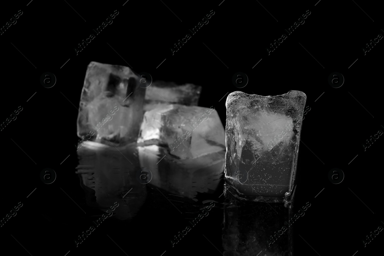 Photo of Transparent ice cubes on black mirror surface