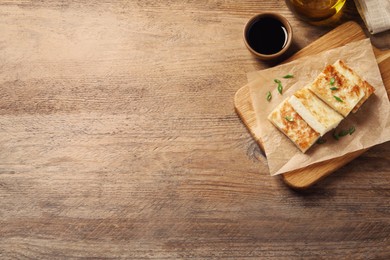 Photo of Delicious turnip cake with green onion and soy sauce on wooden table, flat lay. Space for text
