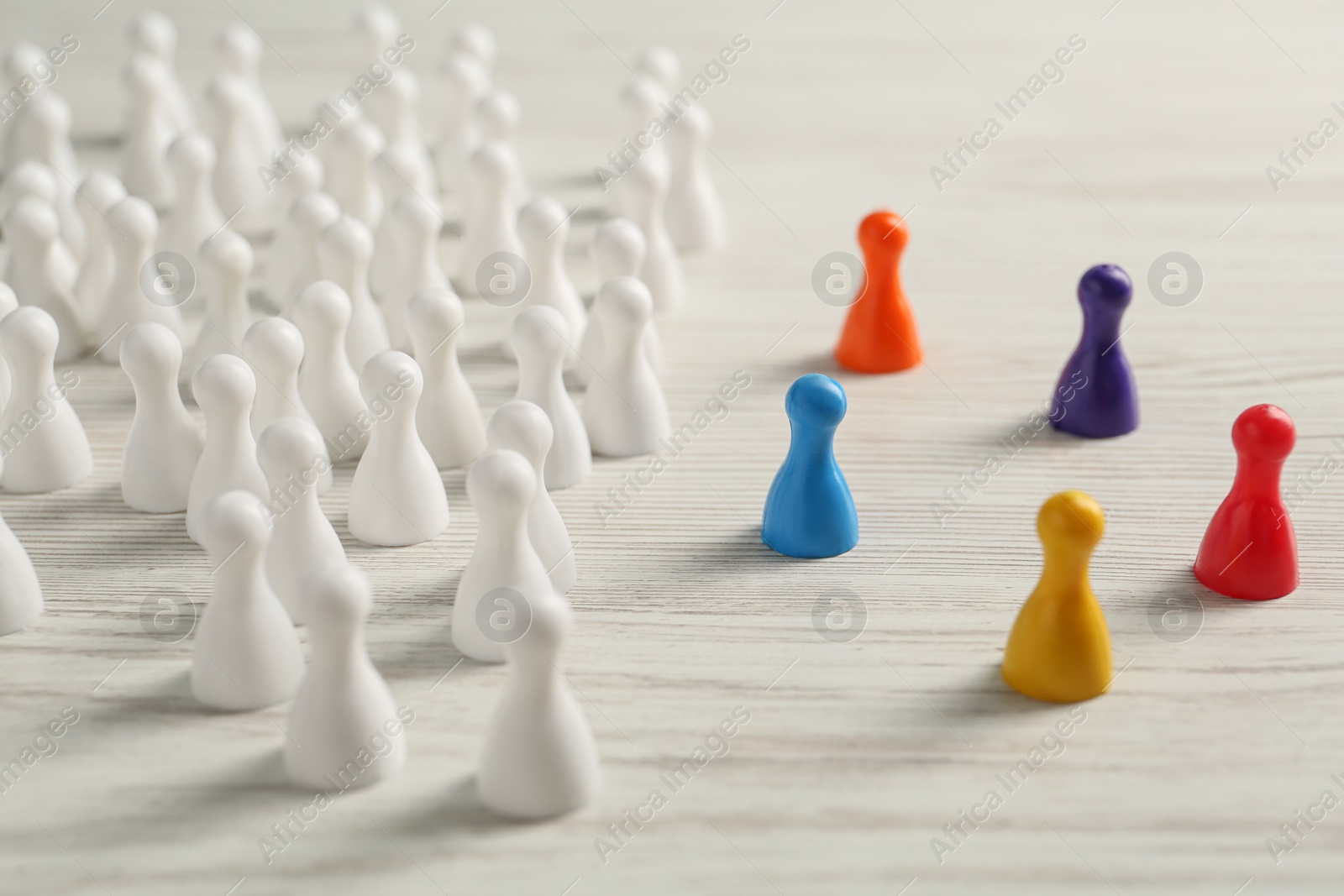 Photo of Colorful pawns on white wooden table. Social inclusion concept