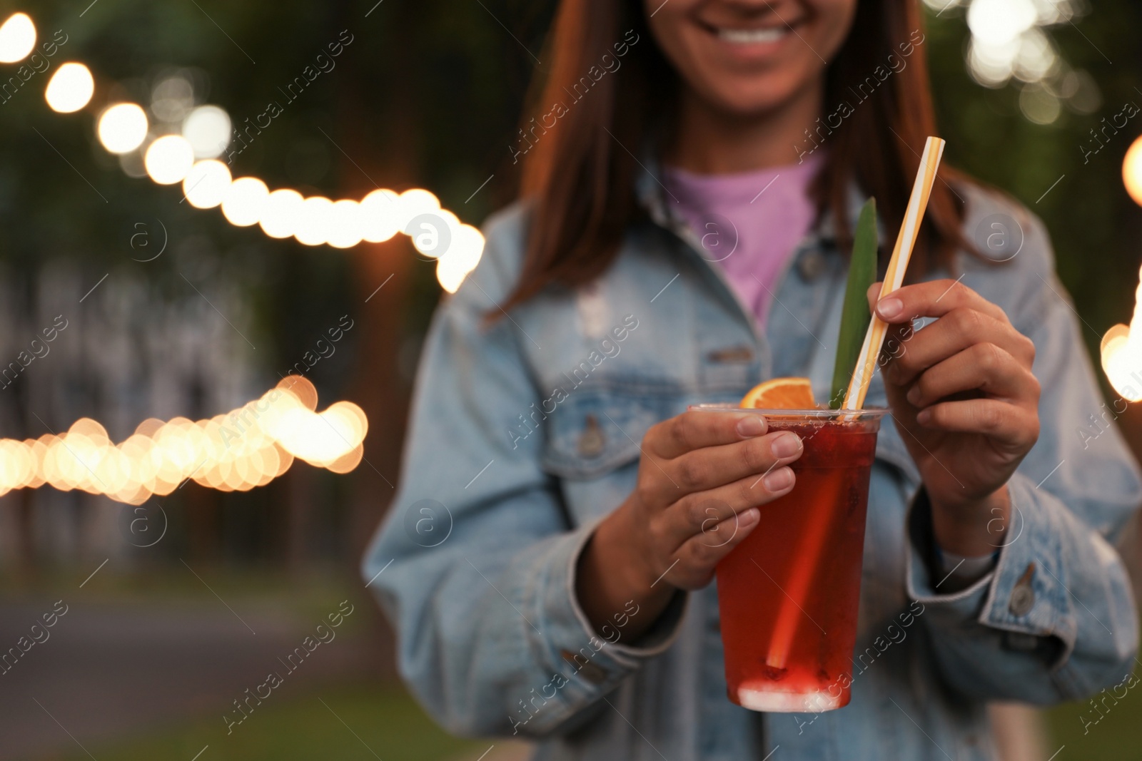 Photo of Young woman with plastic cup of refreshing drink outdoors, closeup. Space for text