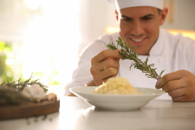 Photo of Professional chef cooking at table in kitchen, focus on hands