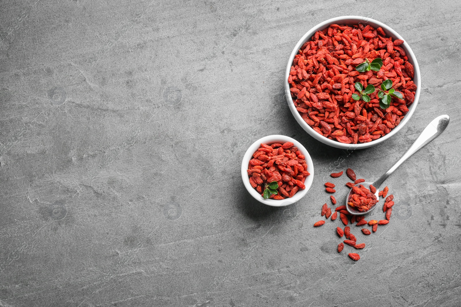 Photo of Flat lay composition with dried goji berries on grey table, space for text. Healthy superfood