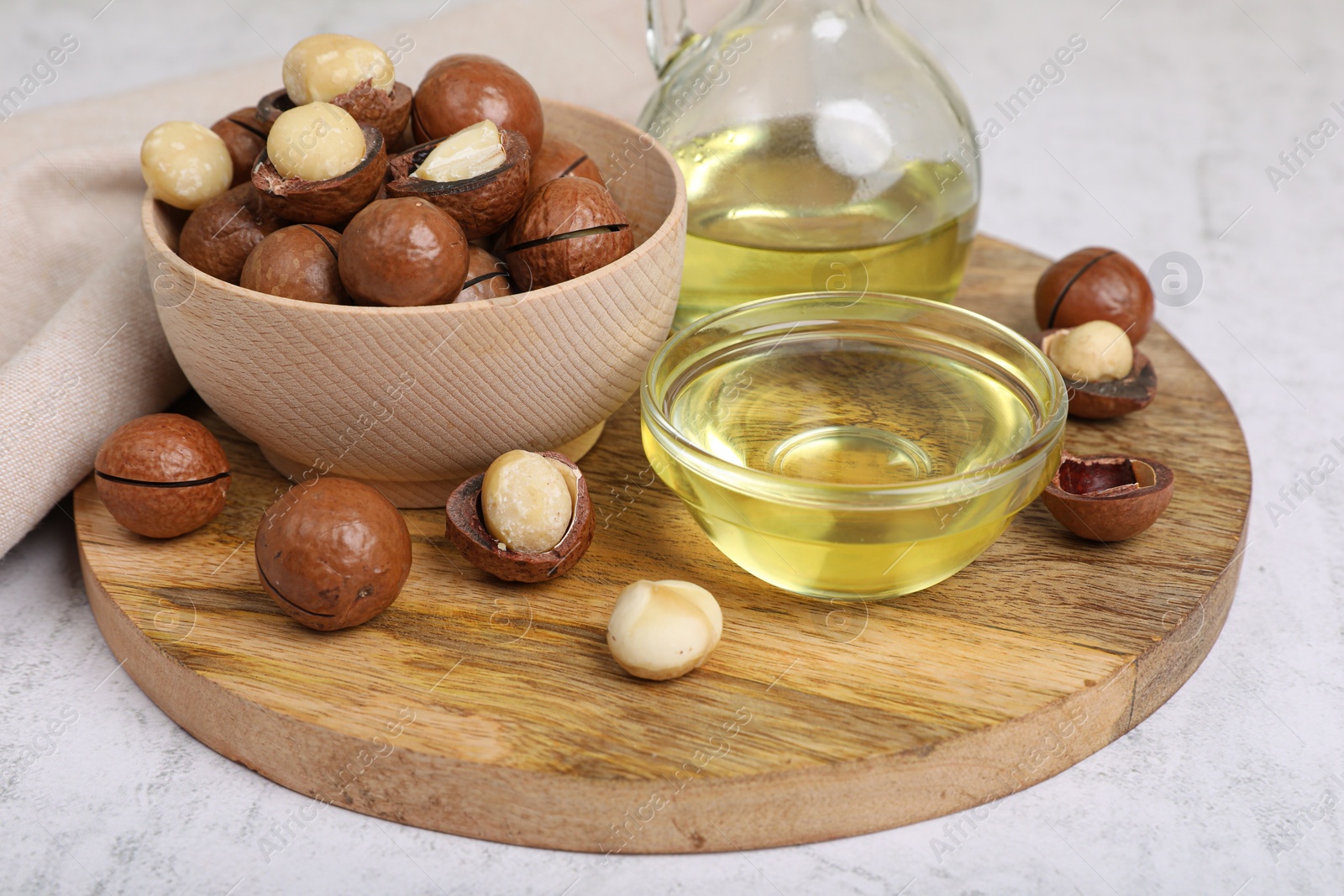 Photo of Delicious organic Macadamia nuts and natural oil on white textured table