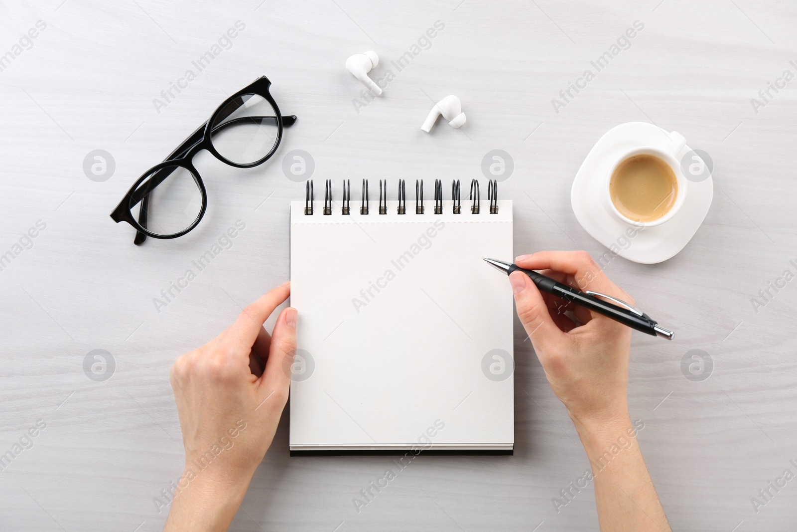 Photo of Woman with notebook and pen at white wooden table, top view. Space for text