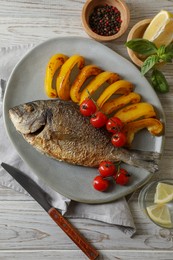 Delicious roasted dorado fish served with vegetables on wooden table, flat lay