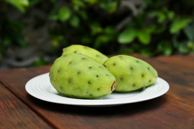 Tasty prickly pear fruits on wooden table outdoors