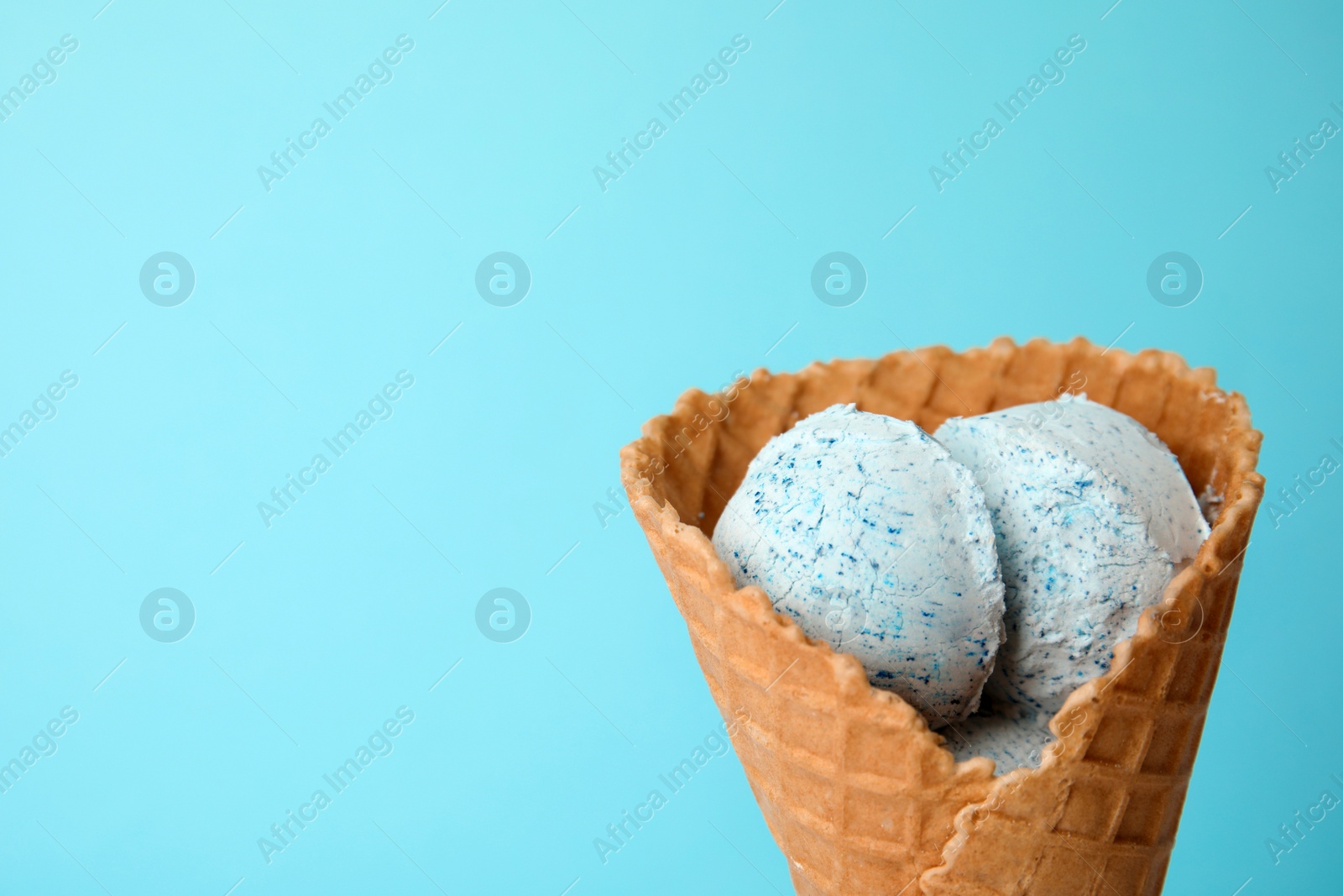 Photo of Delicious ice cream in waffle cone on color background, space for text