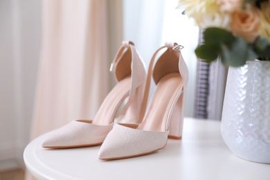 High heeled shoes on white table and beige dress indoors, closeup