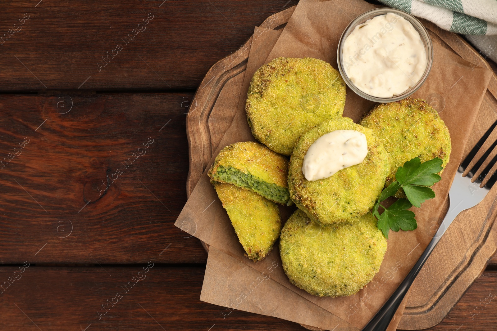 Photo of Tasty vegan cutlets served with sauce and parsley on wooden table, top view. Space for text