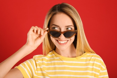 Photo of Beautiful woman in stylish sunglasses on red background