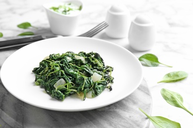 Photo of Plate with tasty cooked spinach on table. Healthy food