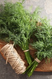 Photo of Bunches of fresh dill and spool of thread on grey textured table, top view