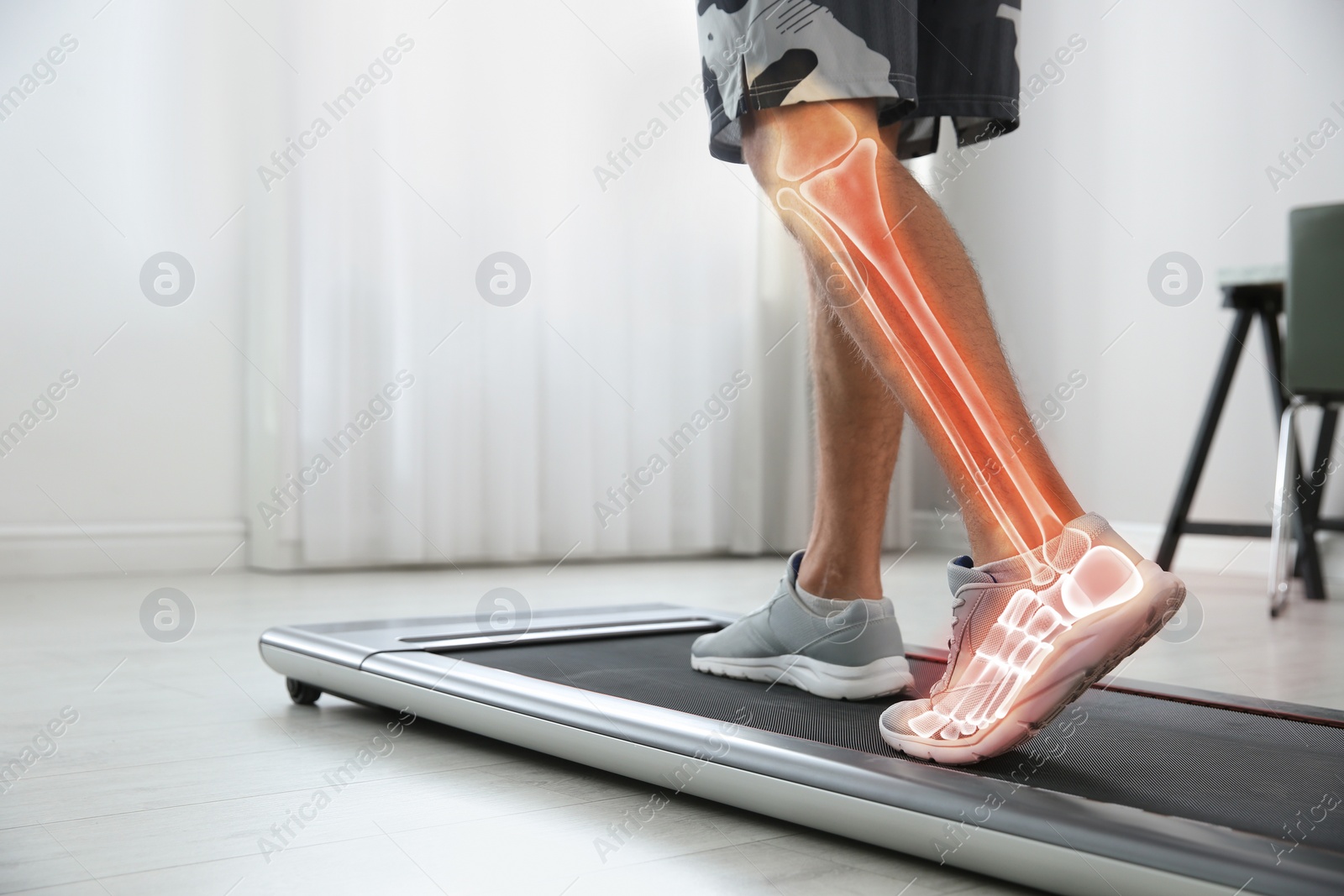 Image of Digital composite of highlighted bones and man training on walking treadmill at home, closeup