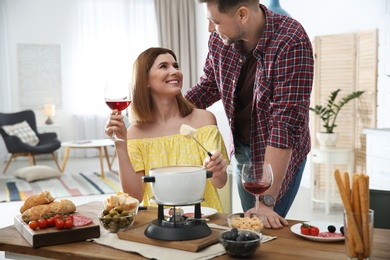 Photo of Happy couple enjoying fondue dinner at home