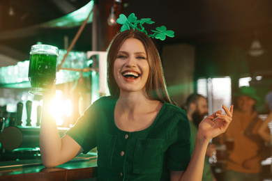 Photo of Young woman with glass of green beer in pub. St. Patrick's Day celebration