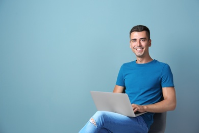 Photo of Man in casual clothes with laptop on color background