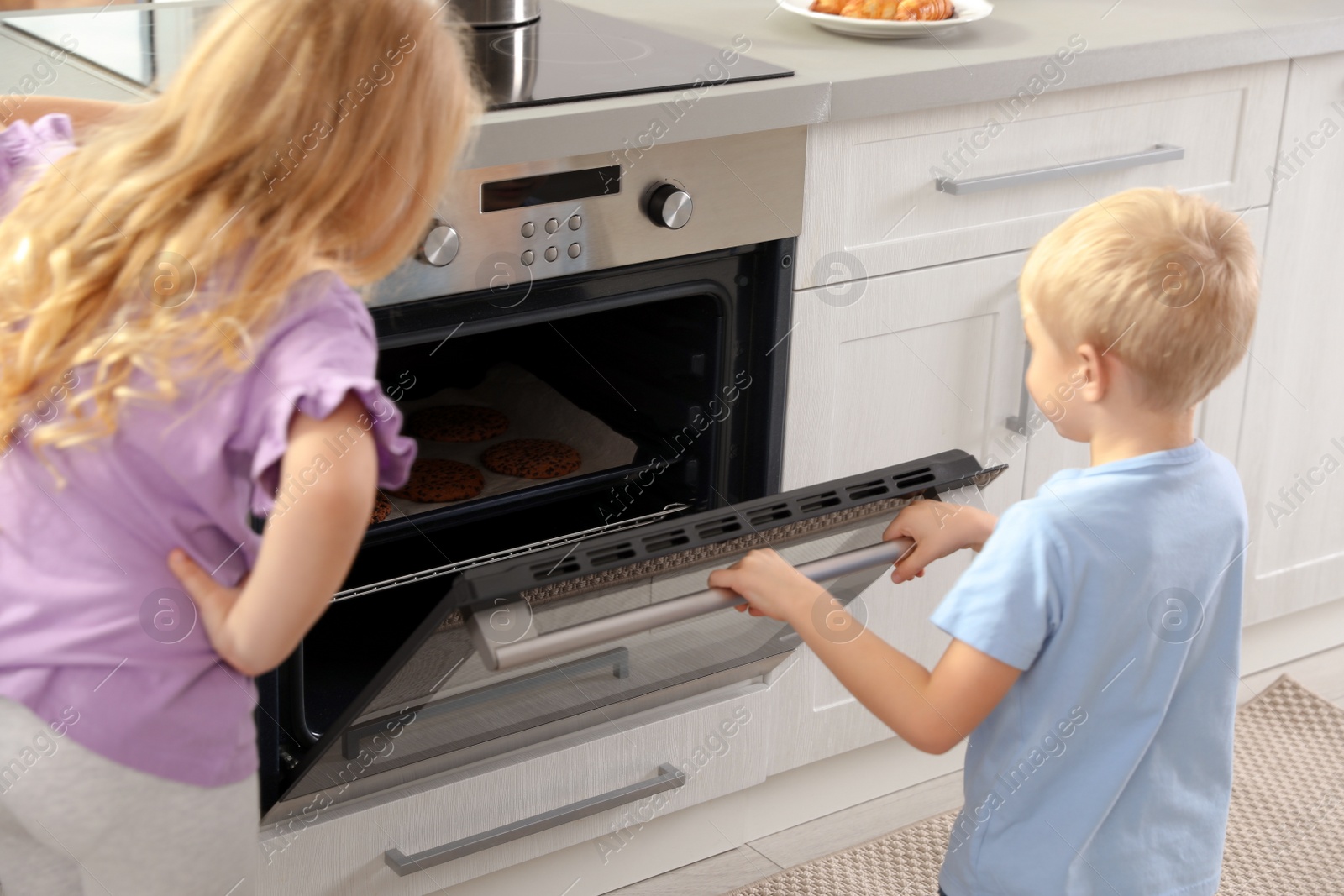 Photo of Little kids baking cookies in oven at home