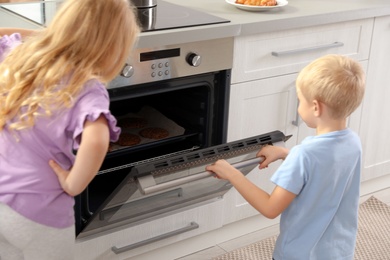 Little kids baking cookies in oven at home