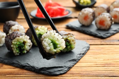Chopsticks and set of delicious sushi rolls on wooden table, closeup