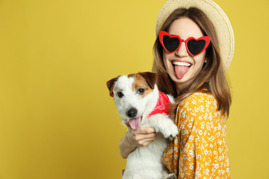 Photo of Young woman with her cute Jack Russell Terrier on yellow background, space for text. Lovely pet