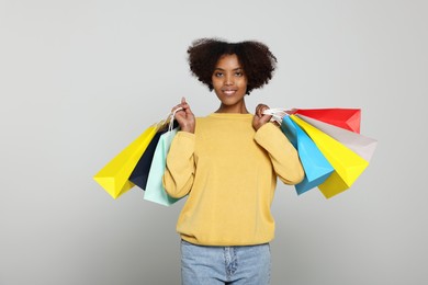 Photo of Happy African American woman with shopping bags on light grey background