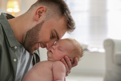 Photo of Father with his newborn son at home