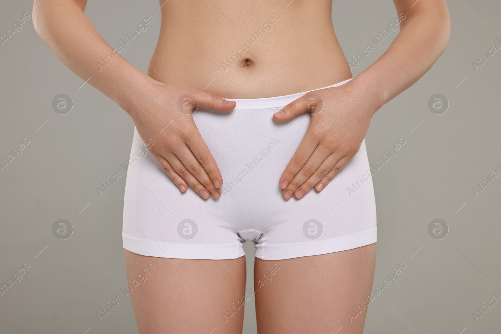 Photo of Woman holding hands near panties on grey background, closeup. Women's health