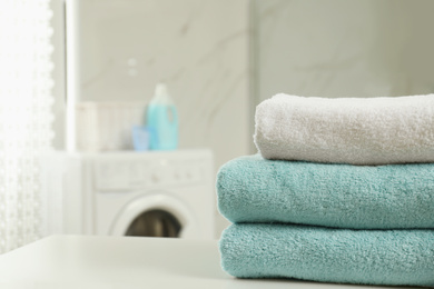 Photo of Stack of clean towels on table in laundry room. Space for text