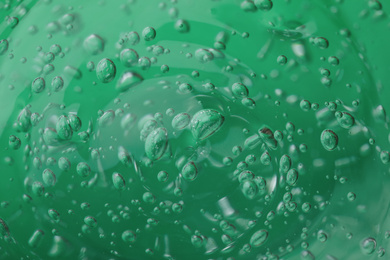 Photo of Pure transparent cosmetic gel on green background, closeup
